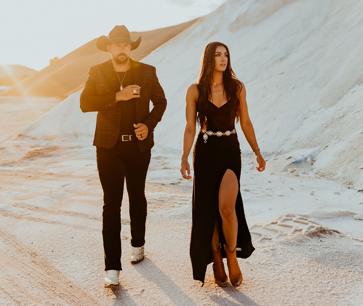 Country duo Tim & Taylor walking through white sand dunes in black western formal wear