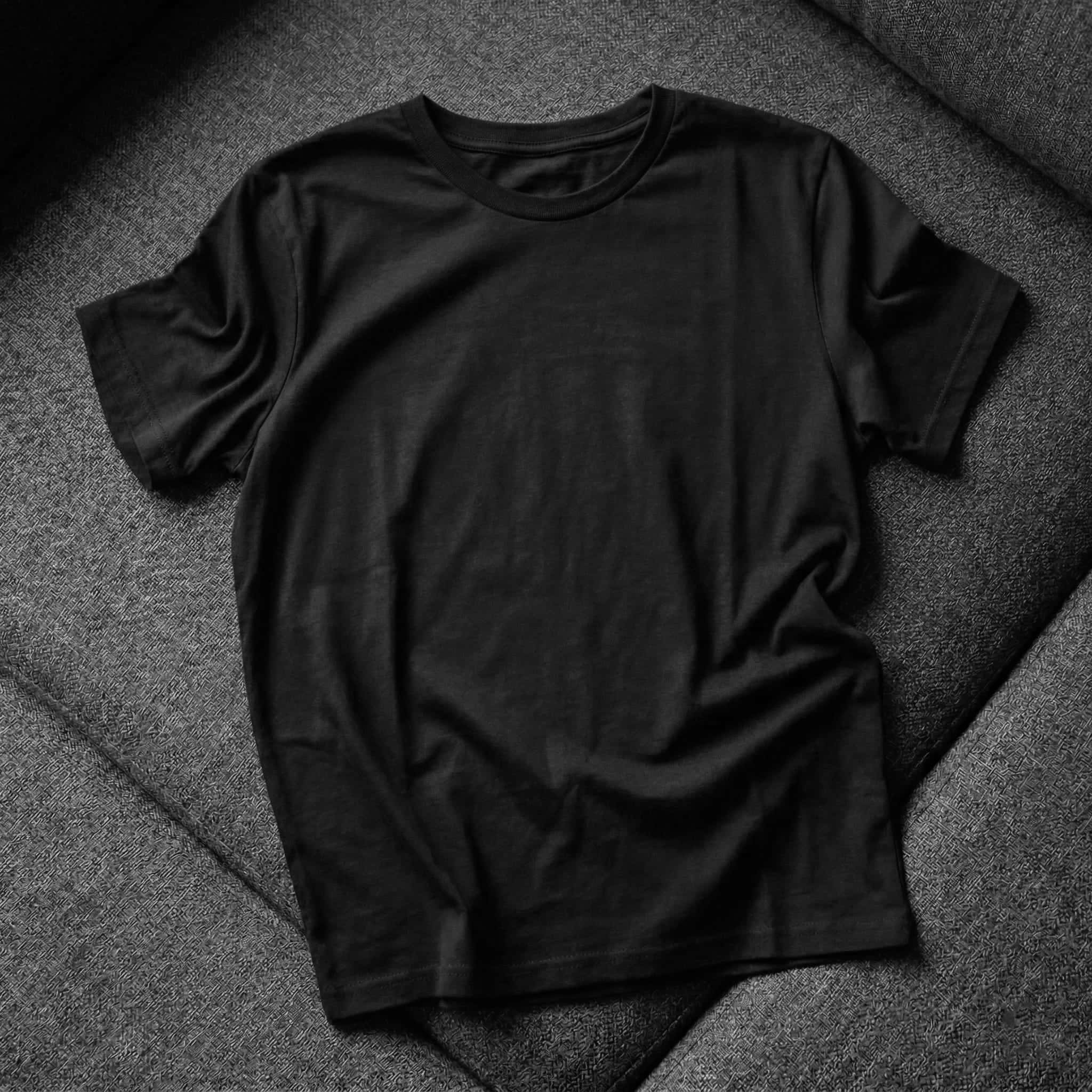 Plain black t-shirt folded on grey fabric, Tim & Taylor merch placeholder image